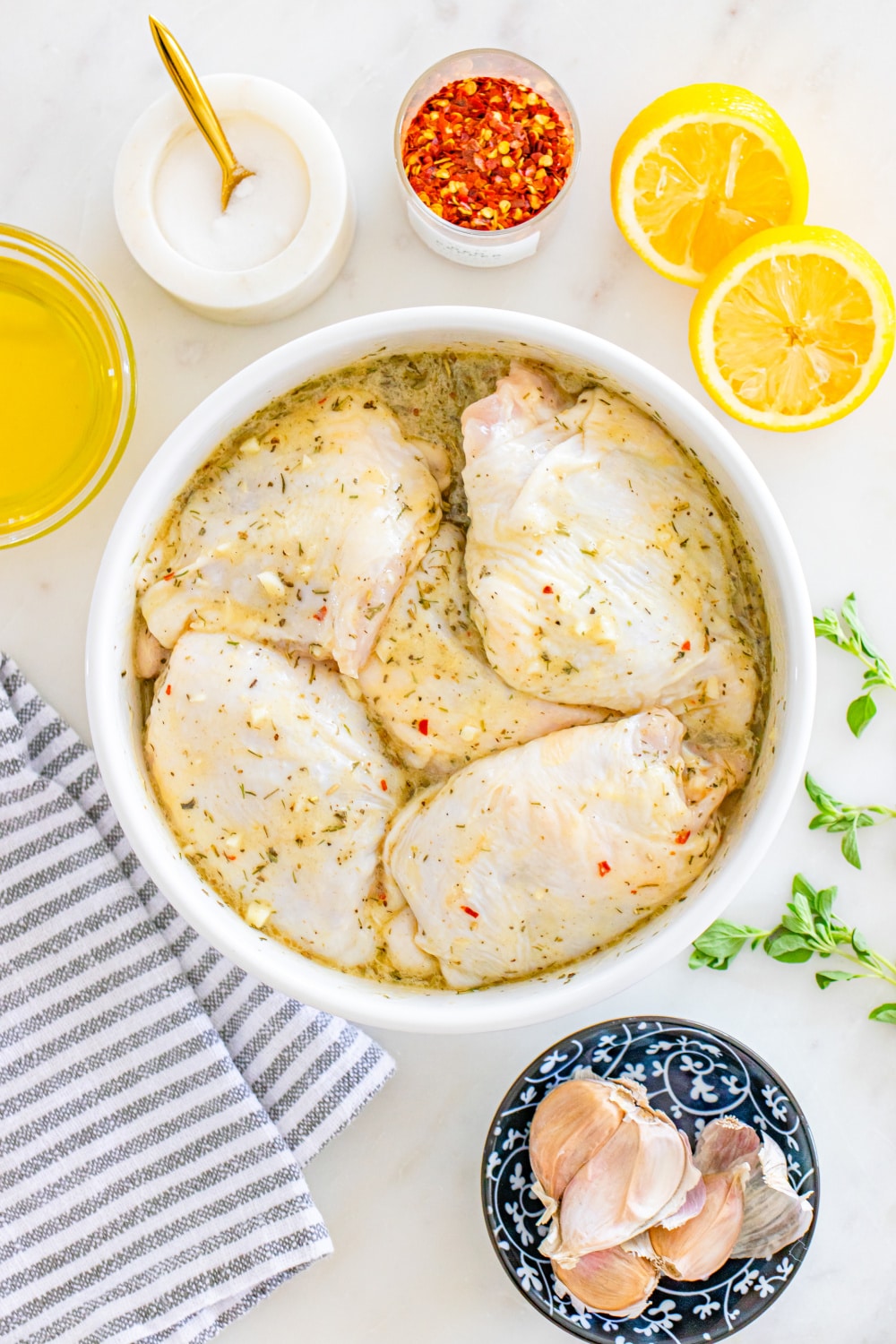 Greek Lemon Chicken Thighs Ingredients on a white marble countertop.