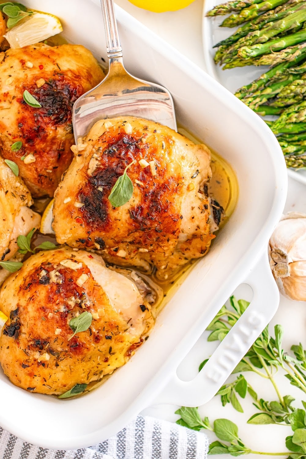 A single chicken thigh being lifted from a pan on a spatula. 