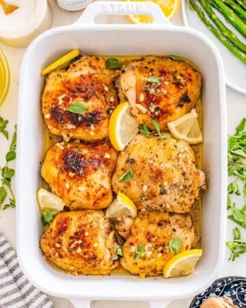Greek Lemon Chicken Thighs baked in a white casserole dish.