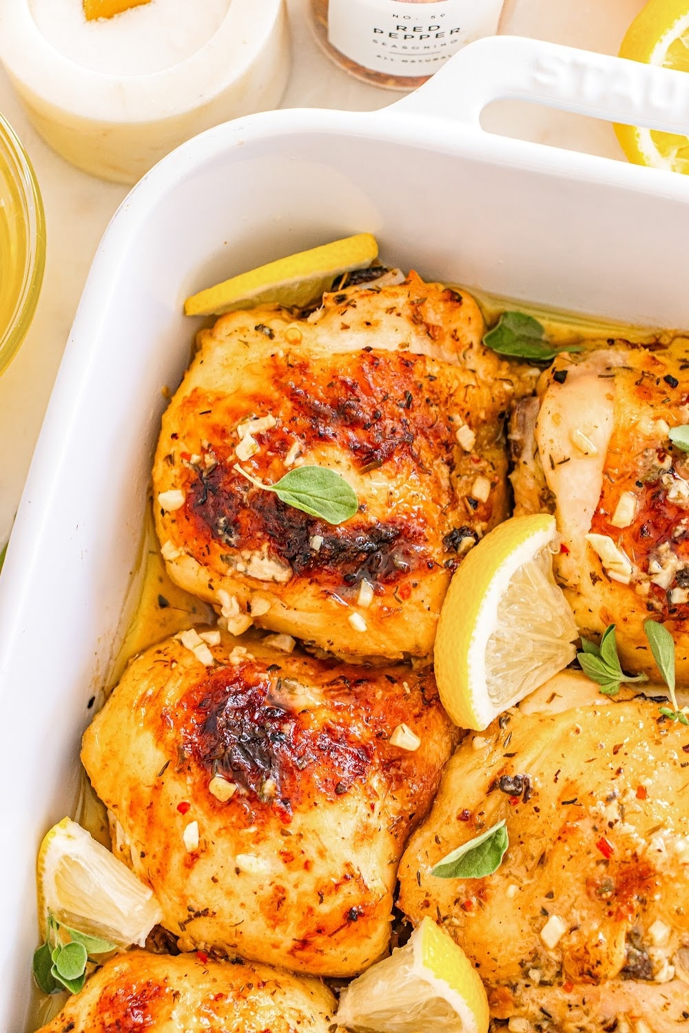 Chicken thigh in a baking dish, with fresh lemon slices. 