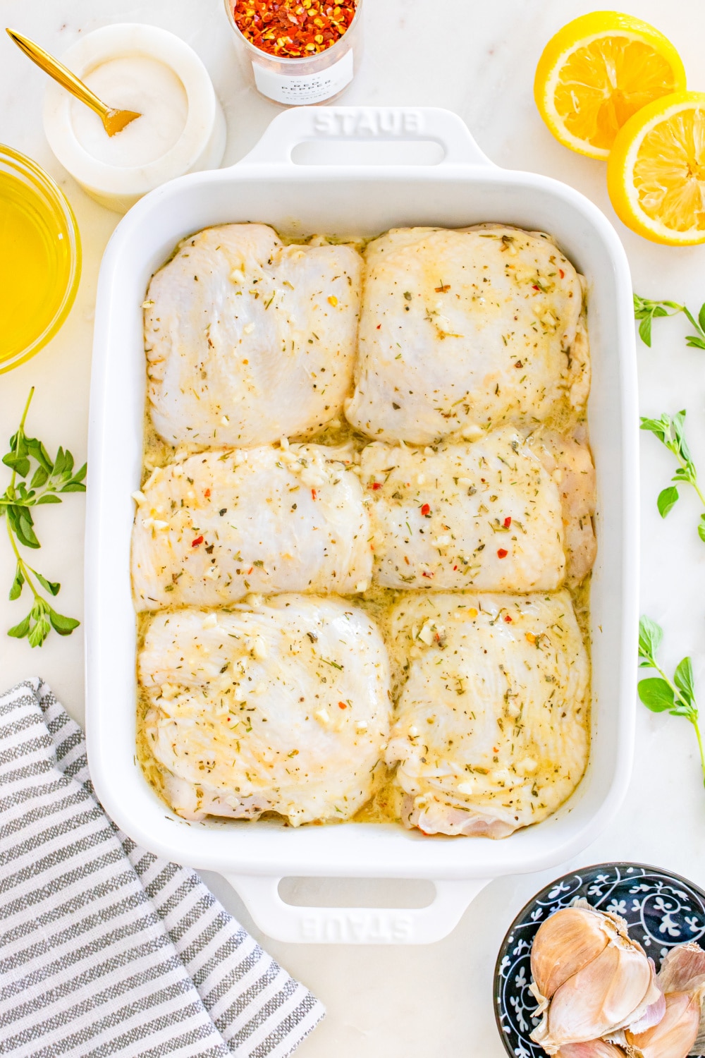 Chicken covered in marinade in a baking dish.