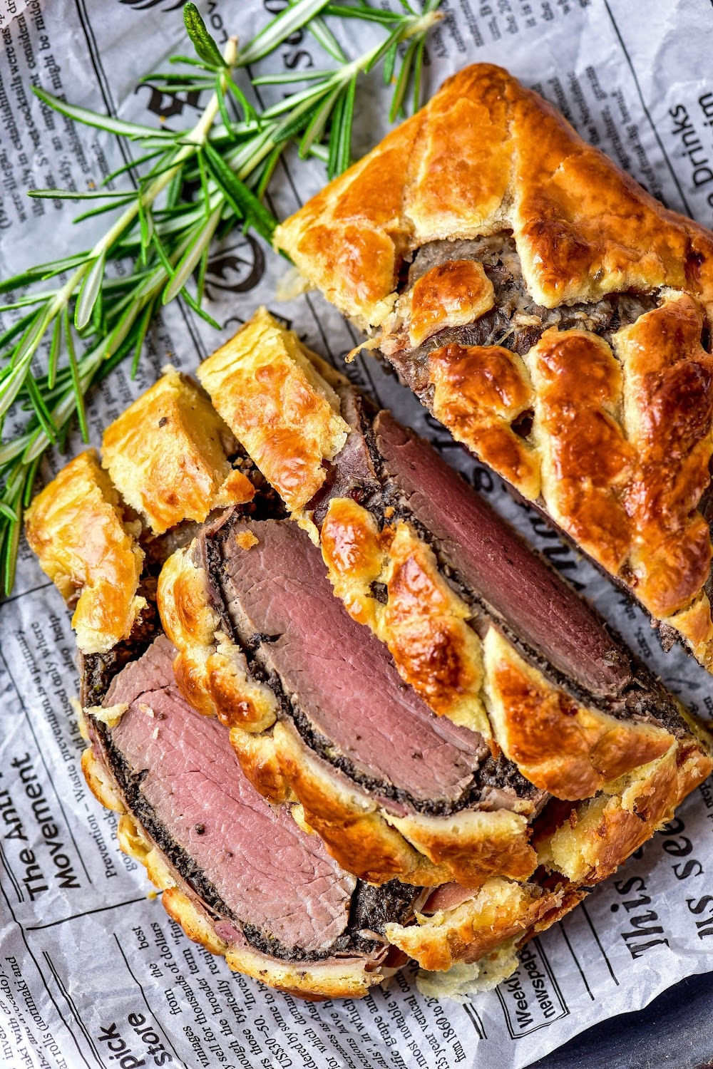 Golden brown Beef Wellington sliced open to show the pink center of the tenderloin.