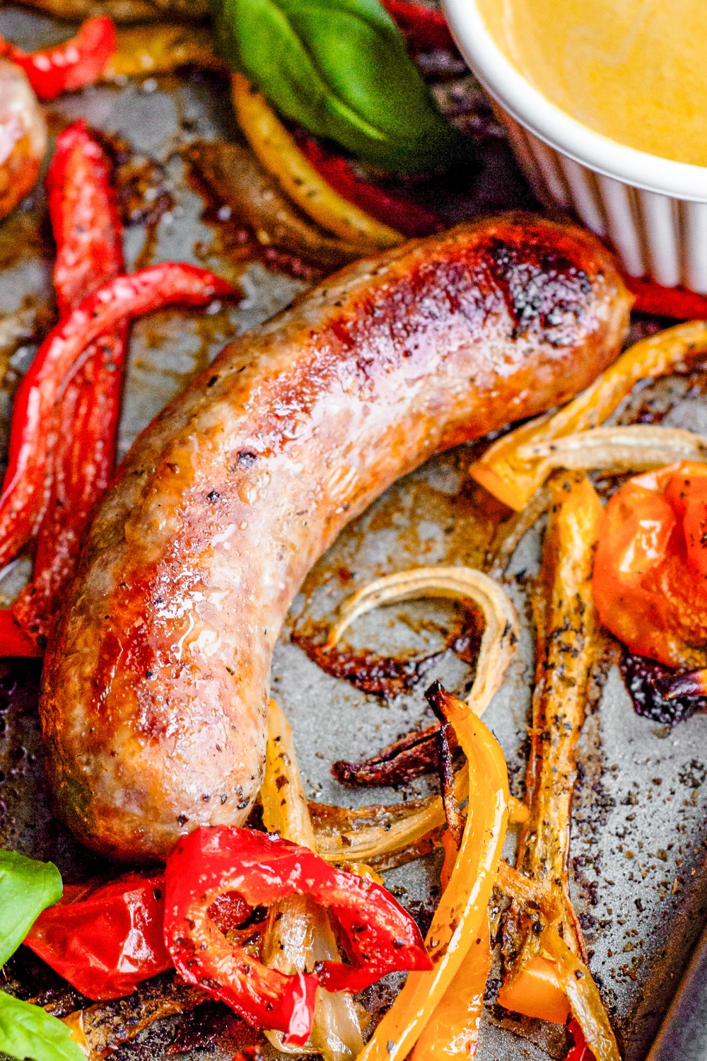 A single cooked Italian sausage surrounded by bell peppers and sliced onions 
