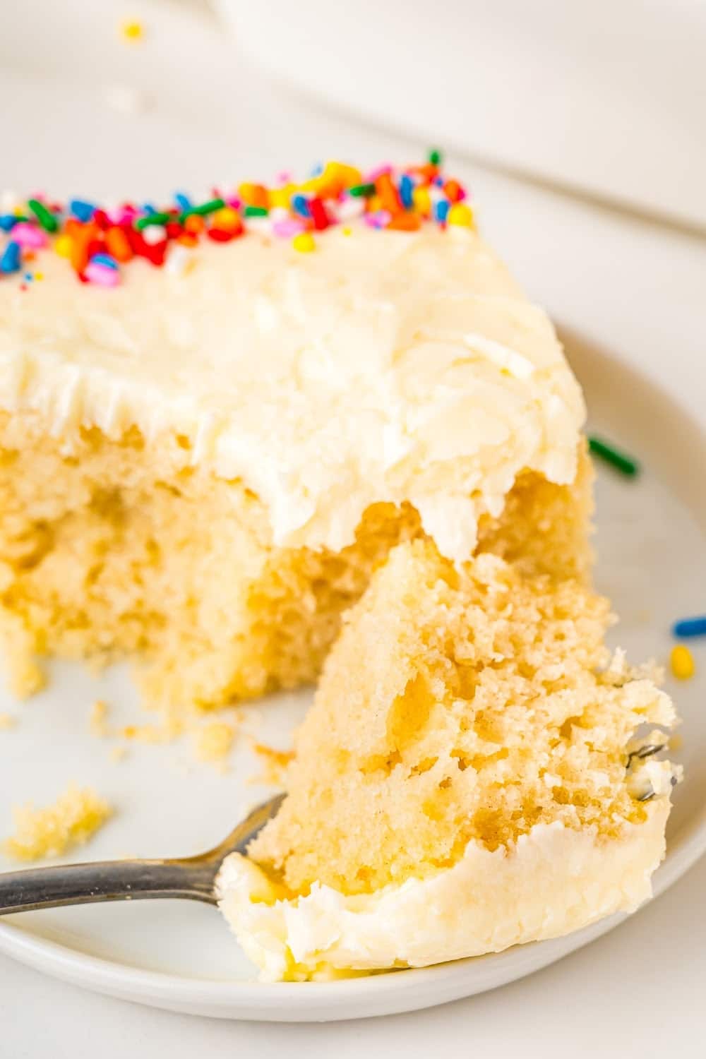 A slice of cake on a plate with homemade butter cream.