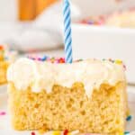 A piece of homemade vanilla sheet cake on dessert plate topped with a birthday candle.