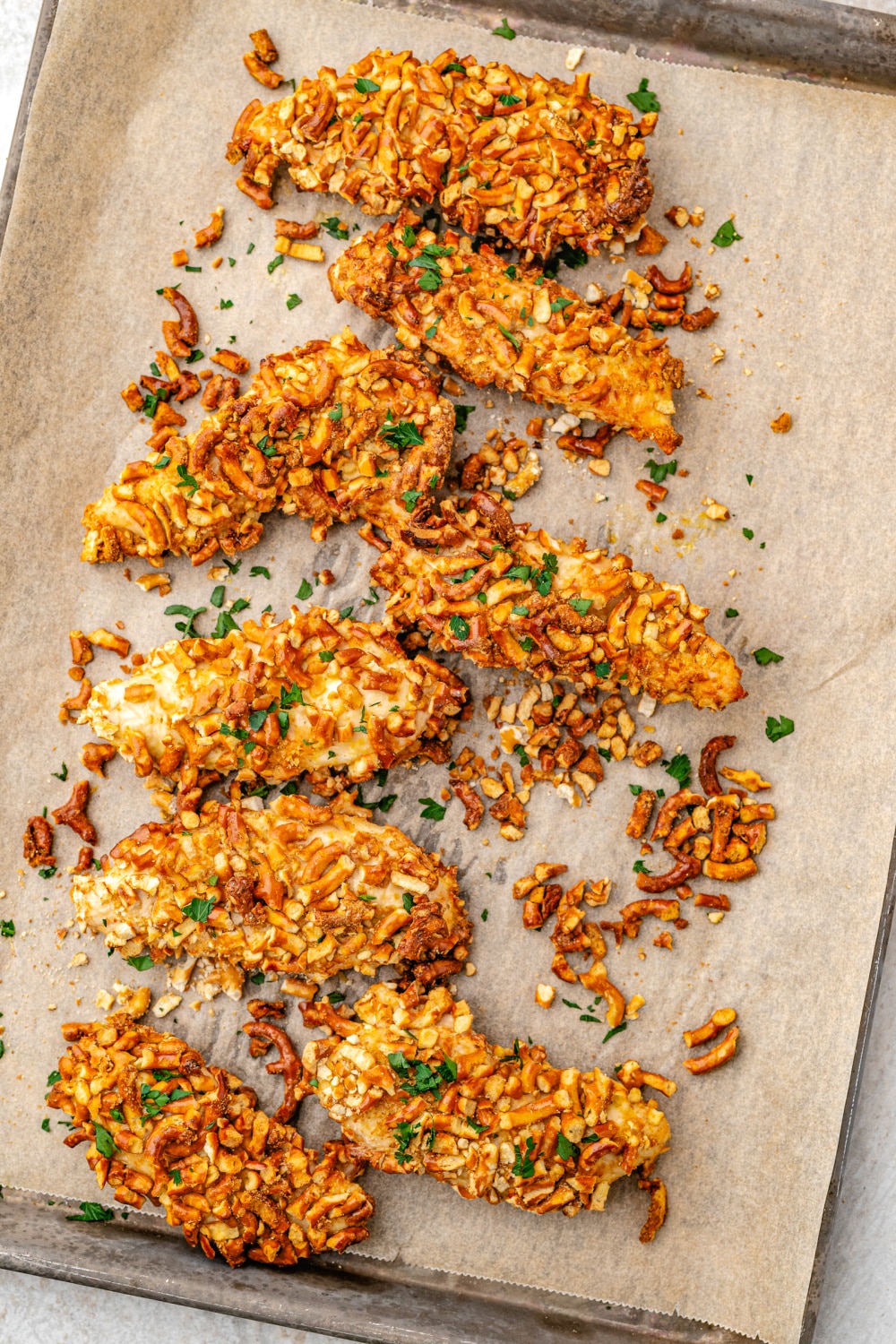 Baked Pretzel Crusted Chicken on a parchment lined baking sheet. 
