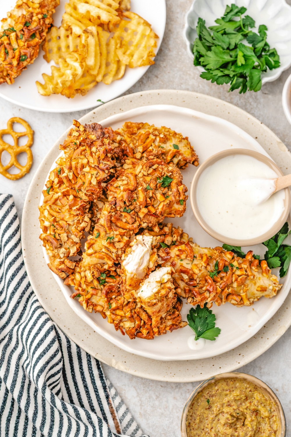 Chicken strips on a plate with a bowl of ranch dipping sauce. 