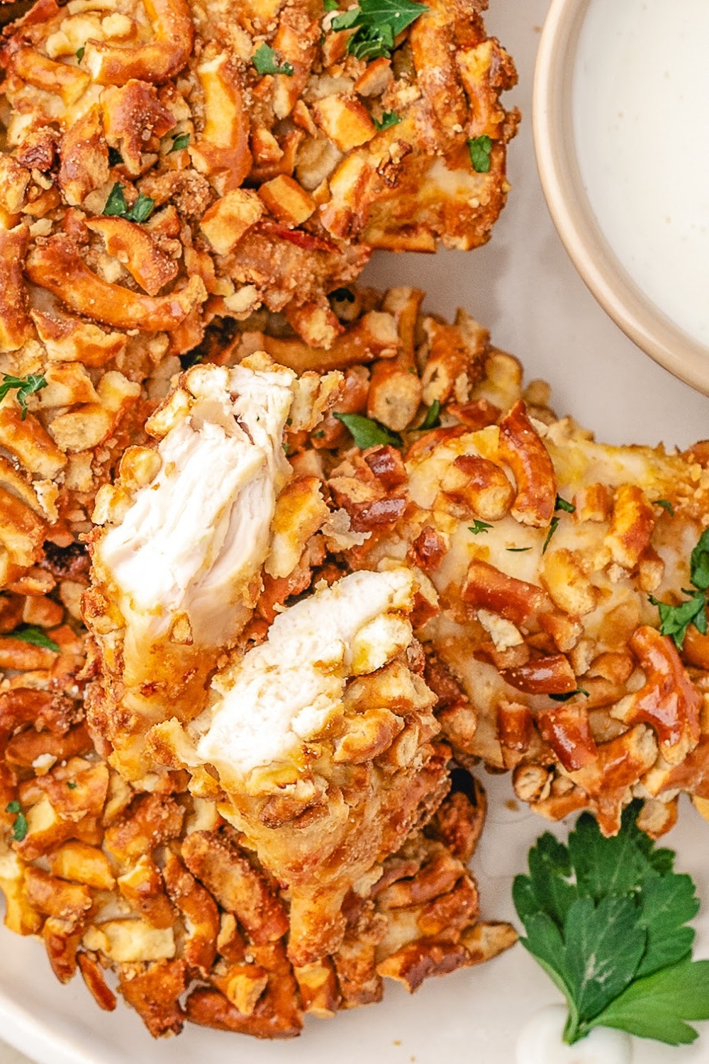 A single piece Pretzel Crusted Chicken cut in half to show the juicy white meat.